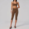A woman wearing a brown two-piece yoga and sports tracksuit set consisting of a cropped top and full-length leggings.