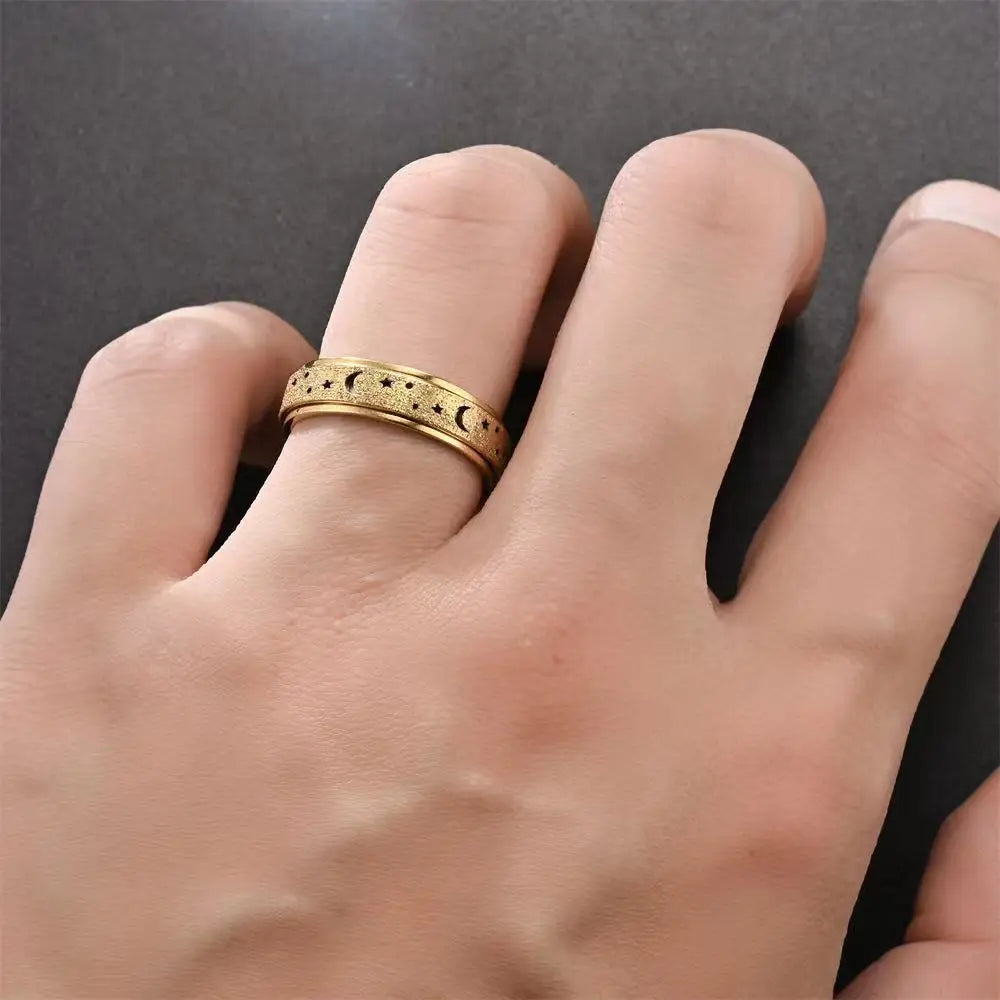 A close-up of a hand wearing a gold-toned stainless steel ring with a moon and star design.