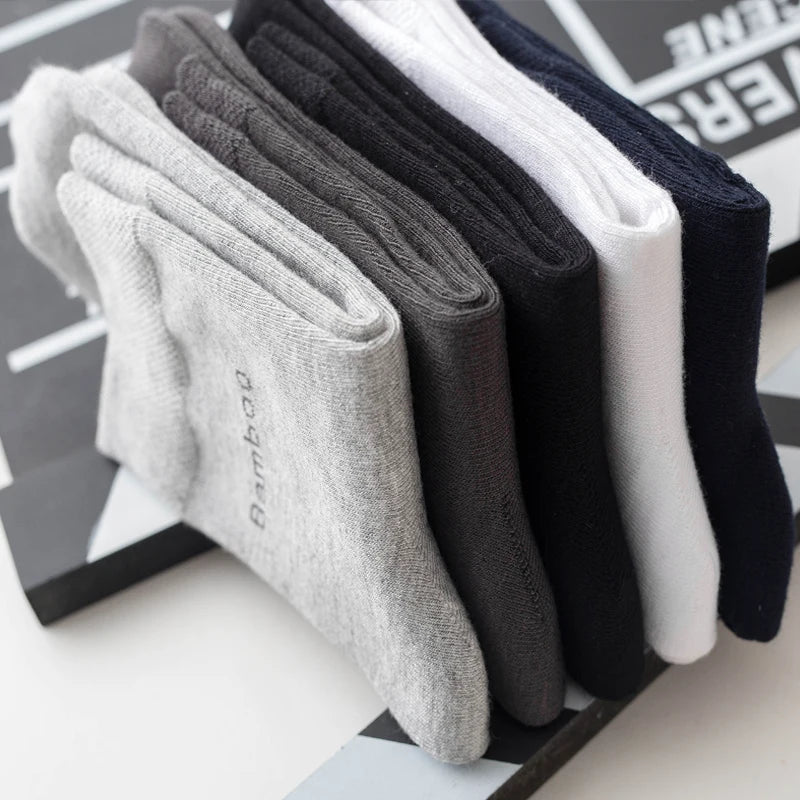 A stack of five men's bamboo fiber socks in various shades of gray, black, and white.