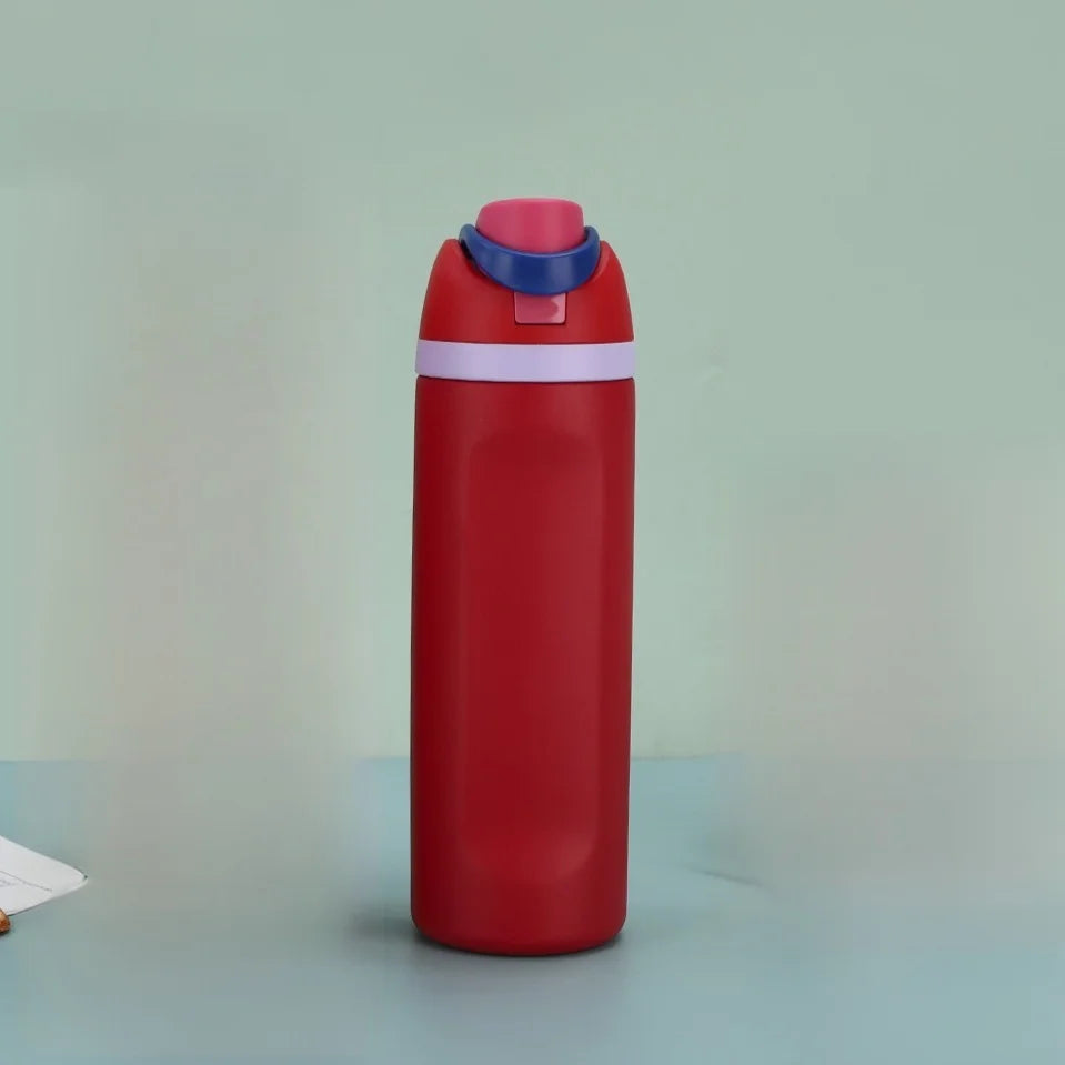 A red insulated stainless steel thermos mug with a blue lid and white band, standing upright on a light surface.