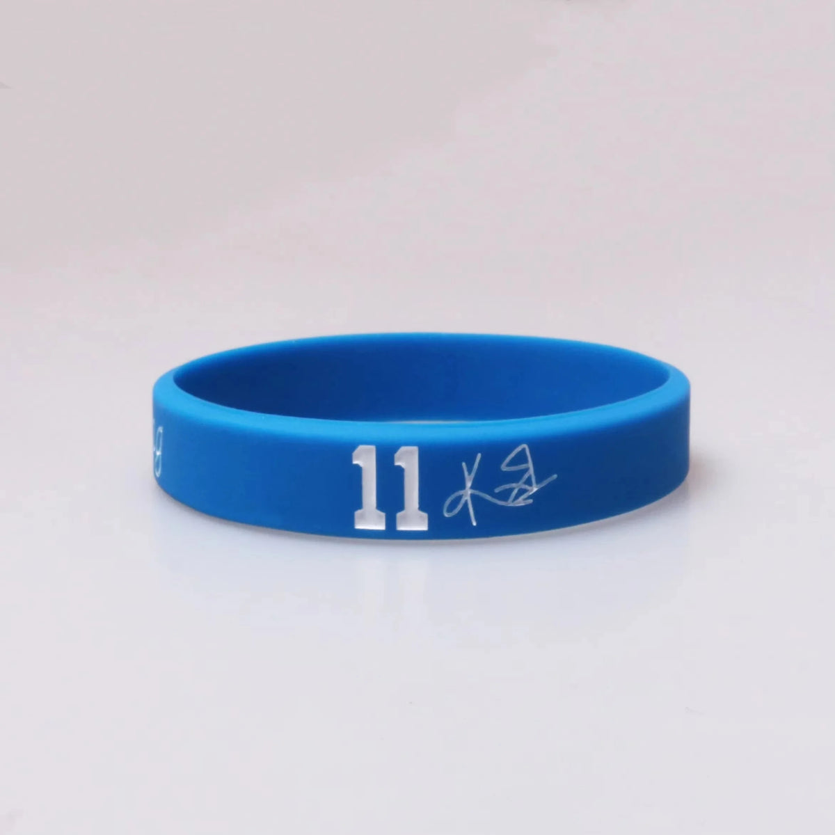 A bright blue silicone wristband with the number 11 and a signature engraved on the surface.
