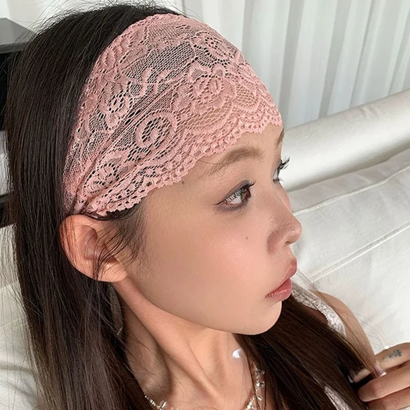 Primer plano de una mujer usando una diadema de encaje floral rosa transparente en la frente, con cabello largo y oscuro.