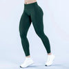A model wearing dark green high-waisted seamless yoga leggings and white sneakers.