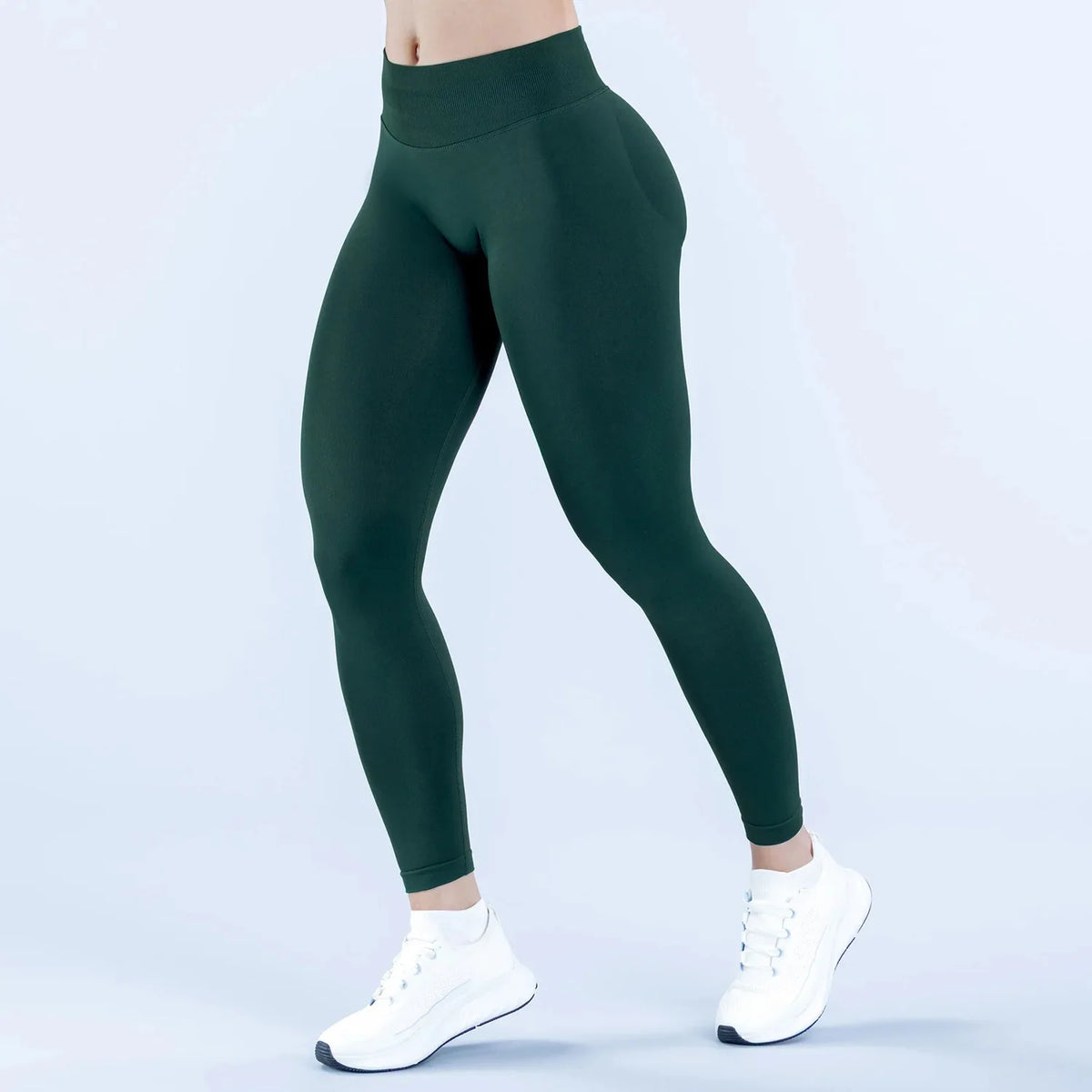 A model wearing dark green high-waisted seamless yoga leggings and white sneakers.