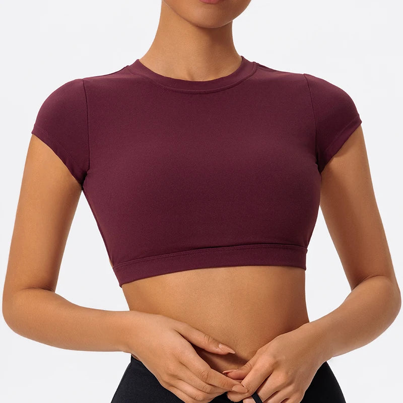 A model wearing a deep burgundy women's fitness crop top yoga and gym t-shirt.