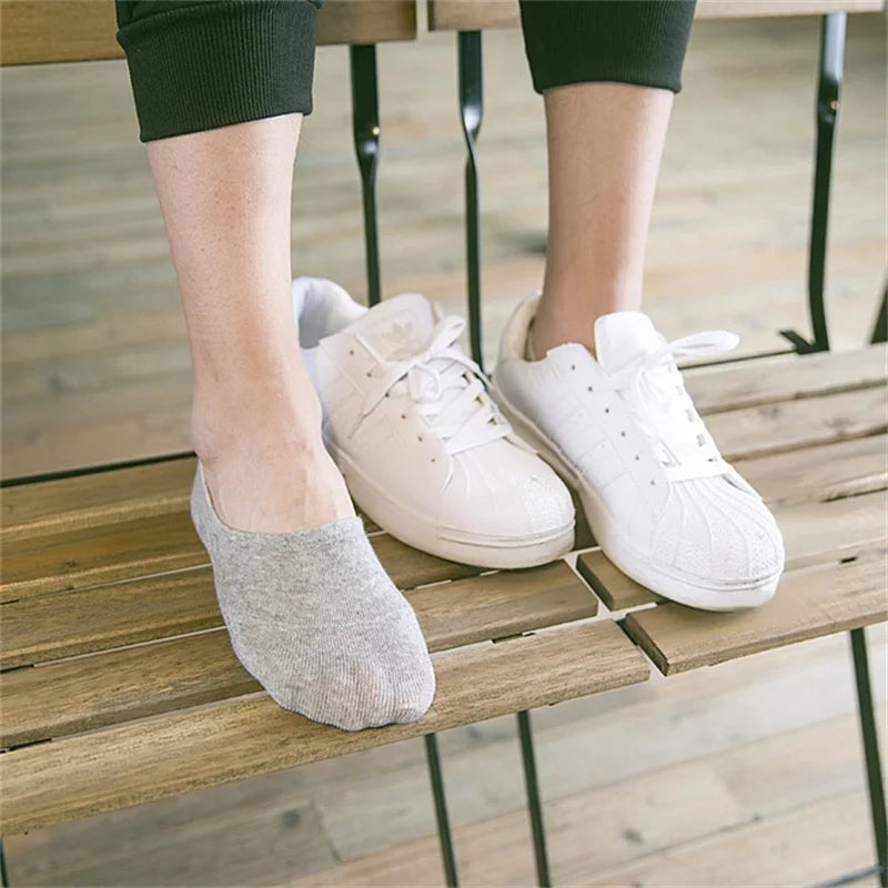 White boat-shaped silicone no-show socks resting on a wooden table.