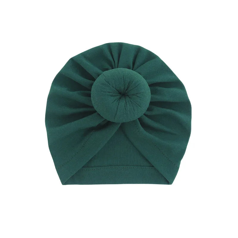 Dunkel-türkises Baumwoll-Babyturban in Rosettenform gefaltet.