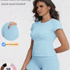 A woman models a light blue sports casual tracksuit top and shorts, showcasing the garment details.