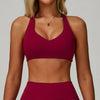A model wearing a maroon padded sport yoga bra with a gold necklace.