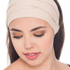 A woman wearing a beige extra wide boho headband on her hair, looking down.