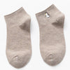 A pair of light beige cotton socks embroidered with a small white bird.