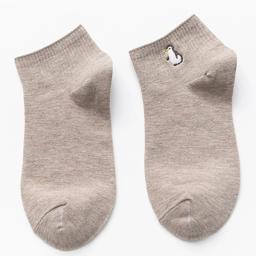 A pair of light beige cotton socks embroidered with a small white bird.