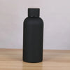 A matte black double-layer vacuum thermos cup with a black cap sitting on a wooden surface.