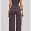 A woman models a dark plum colored women's premium fitness tracksuit top and pants.