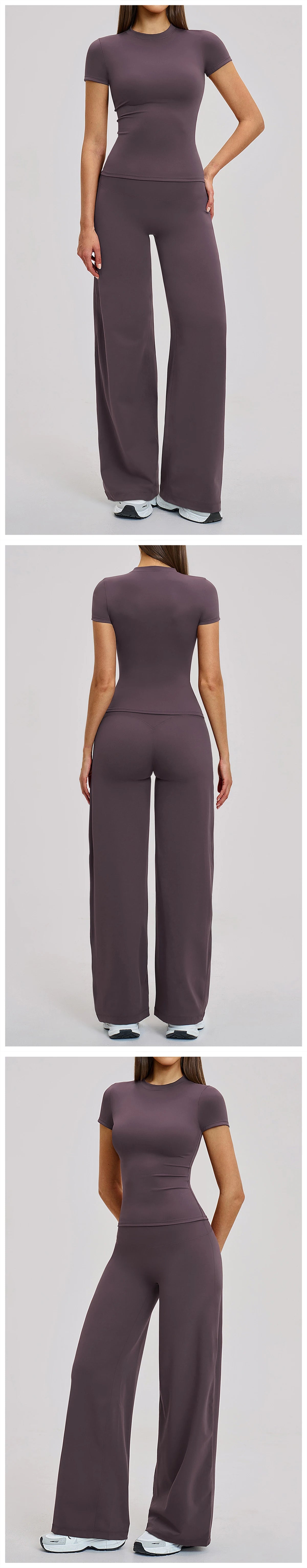A woman models a dark plum colored women's premium fitness tracksuit top and pants.