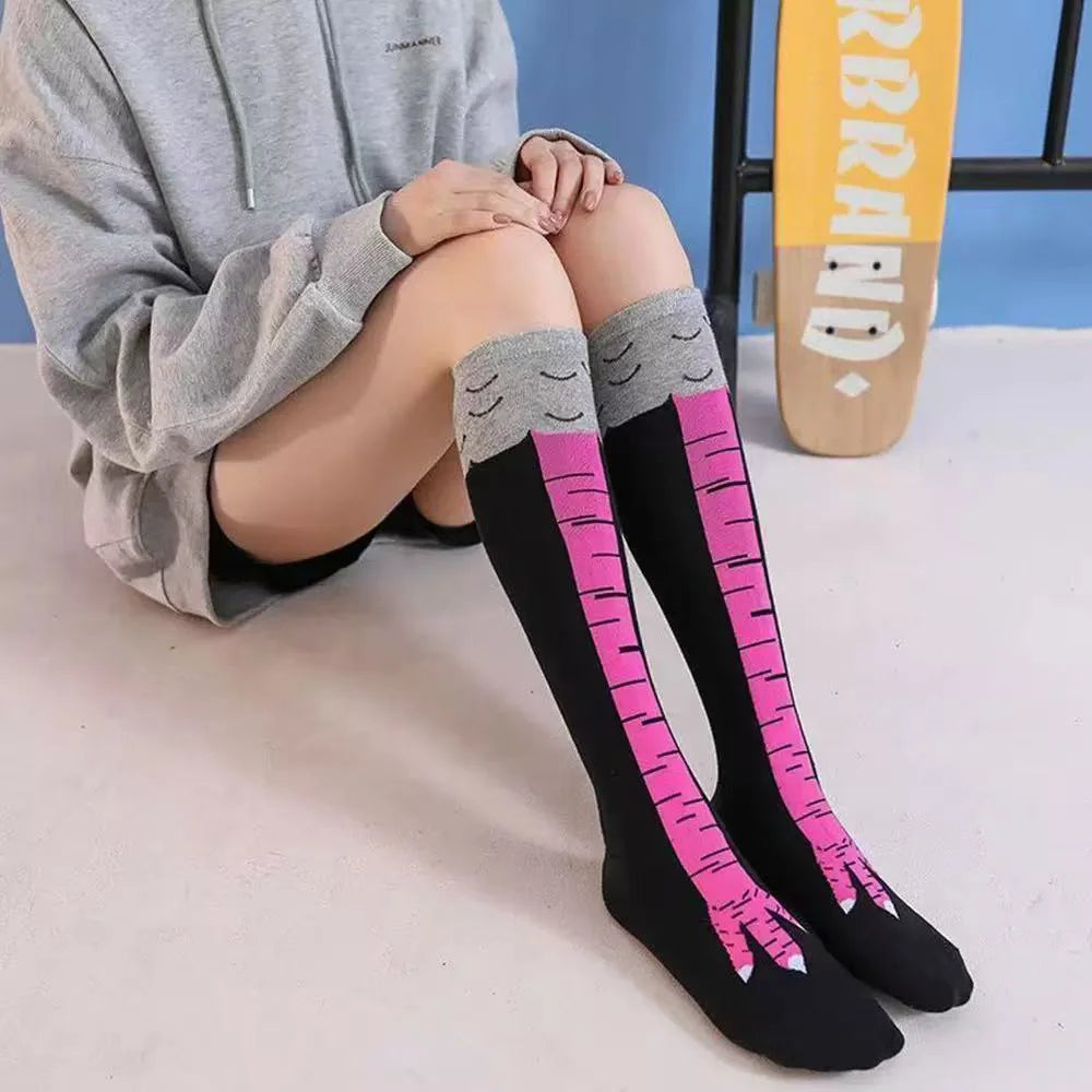 Une personne porte des chaussettes noires montantes avec des rayures roses et des poignets gris, assise sur une surface blanc