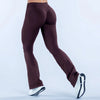 A model wearing dark plum seamless flared yoga leggings and white sneakers.