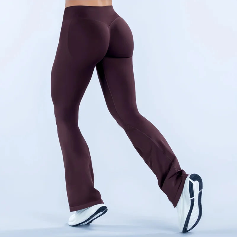 A model wearing dark plum seamless flared yoga leggings and white sneakers.