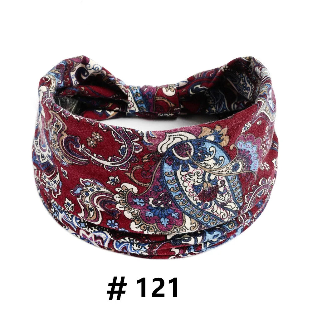 A close-up of a burgundy and blue paisley print cotton headband for hair or workout.