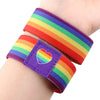 A colorful LGBT stretch wristband bracelet featuring a rainbow stripe and a heart design on a person's wrist.
