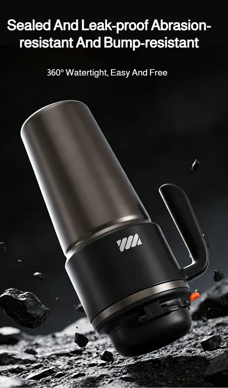A close-up shot of a matte black insulated stainless steel tumbler with a handle and straw resting on rough, dark terrain.