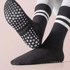 A pair of black non-slip yoga socks with white dots and stripes shown on a foot.