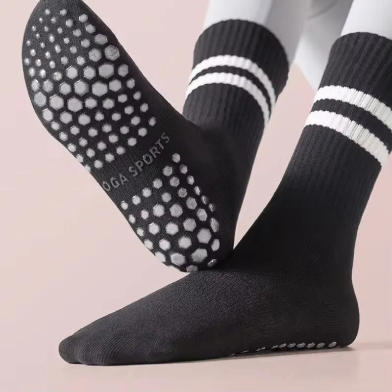 A pair of black non-slip yoga socks with white dots and stripes shown on a foot.