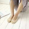 Par de calcetines de silicona de encaje beige sin dedos usados por una mujer con ropa gris claro.