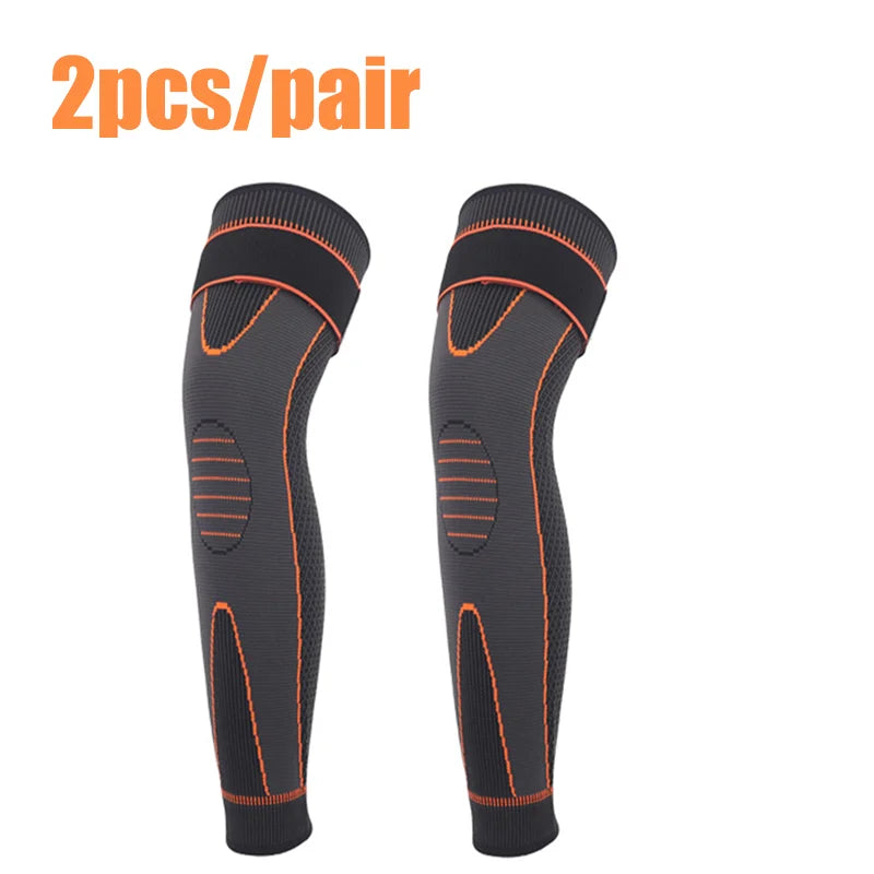 Une paire de genouliers élastiques noirs avec des accents orange sur fond blanc.