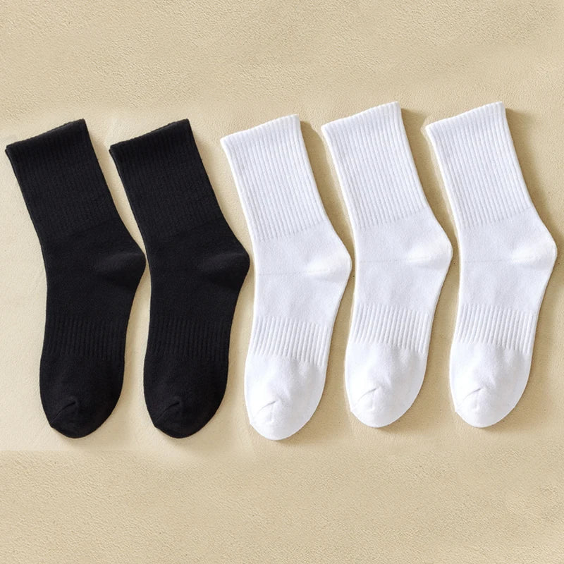 Une rangée de six chaussettes en coton mélangé pour hommes, noires et blanches, sont disposées sur un fond clair.