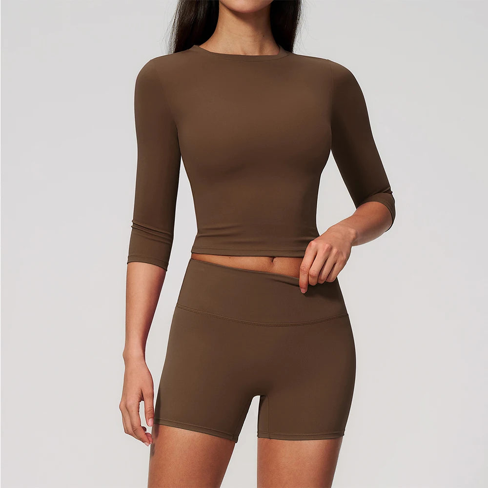 A woman wearing a solid brown long-sleeved top and matching high-waisted leggings set for yoga or fitness.
