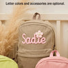 Grauer Samtledertasche mit dem Namen Sadie und einer rosa Blume vor hellem Hintergrund.