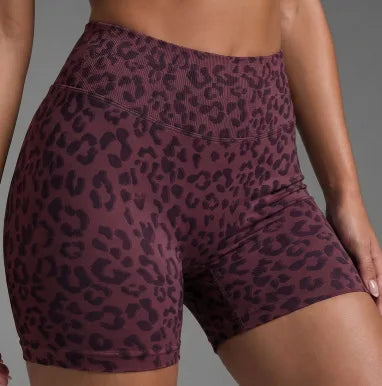 Un mannequin porte des shorts de yoga à taille haute à imprimé léopard violet foncé.