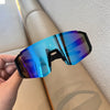 A hand holds a pair of blue-tinted cycling sunglasses against a light background.