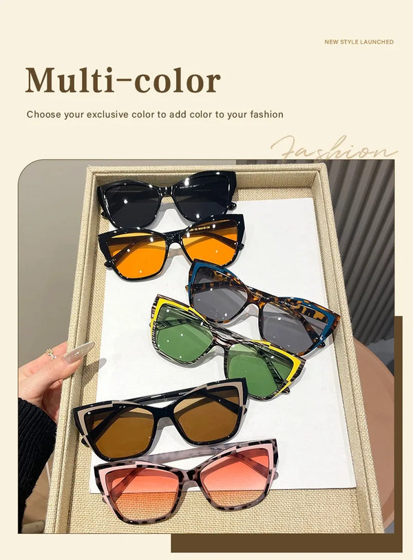 A collection of multi-color sunglasses displayed in a wooden box, showing various shades of black, orange, green, and brown.