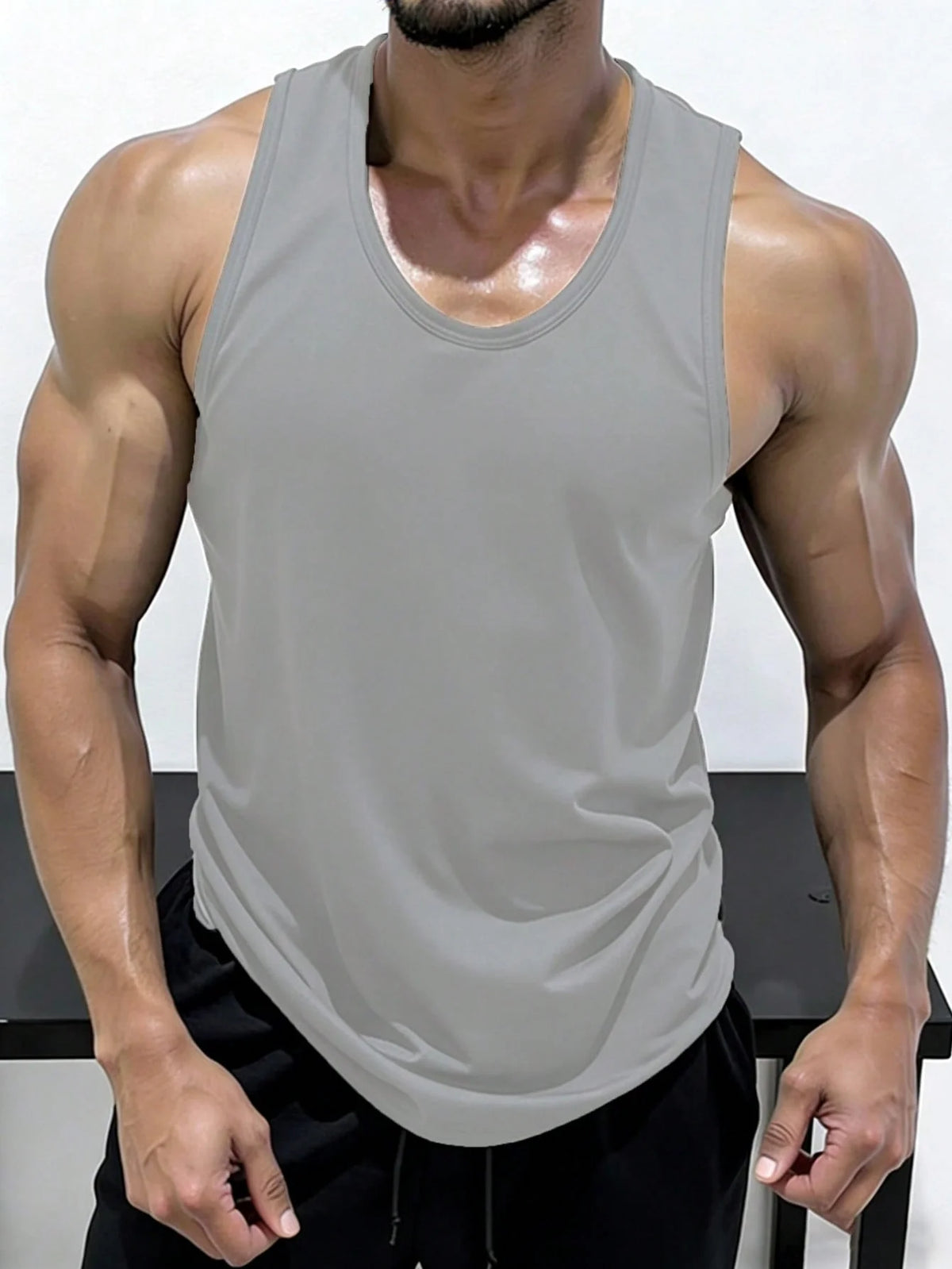 A muscular man wearing a gray sleeveless tank top and black shorts.