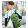 A young man wearing a white and yellow athletic jacket carrying a large olive green waterproof hiking backpack outdoors.
