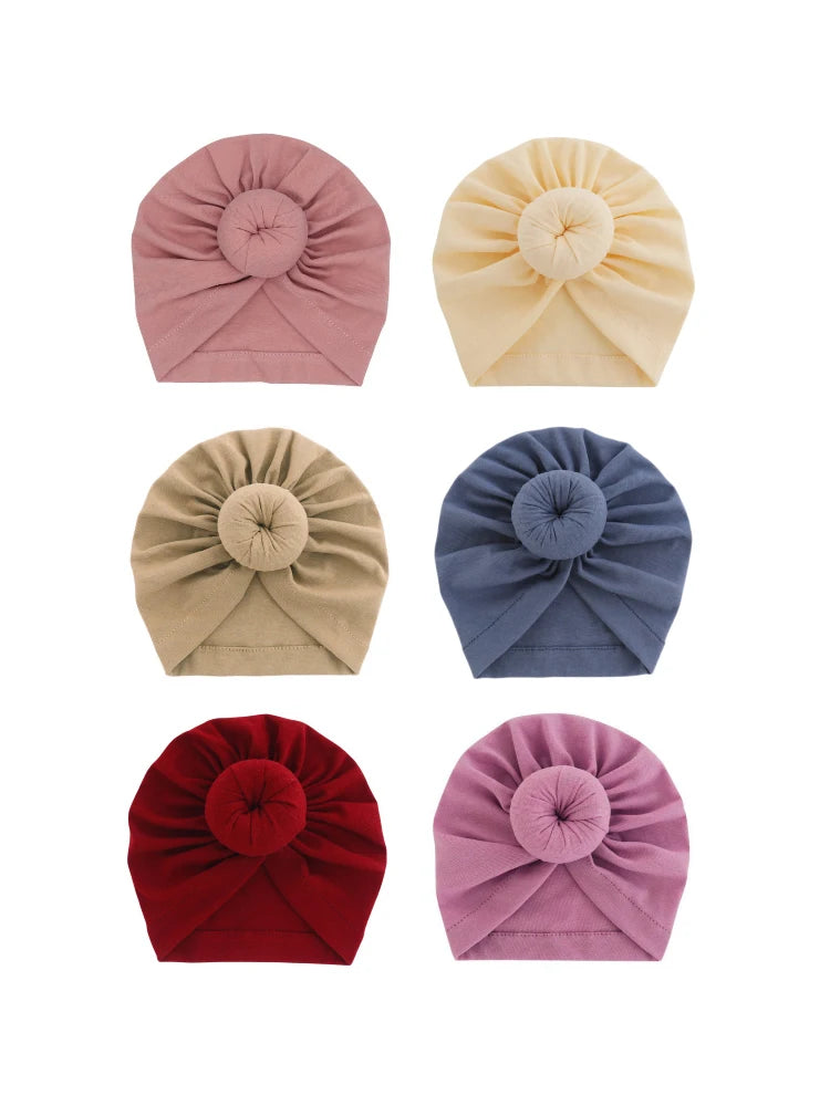 Eine Kollektion von fünf aus festem Baumwoll-Baby-Turban-Headwraps in Rosa, Beige, Blau und Rot.