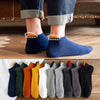 Eine Sammlung von Herren-Baumwoll-Dämpfersocken in verschiedenen Farben und Schattierungen auf einer Holzoberfläche.