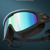 A pair of black swimming goggles with a clear, wide-angle lens are shown against a dark background.