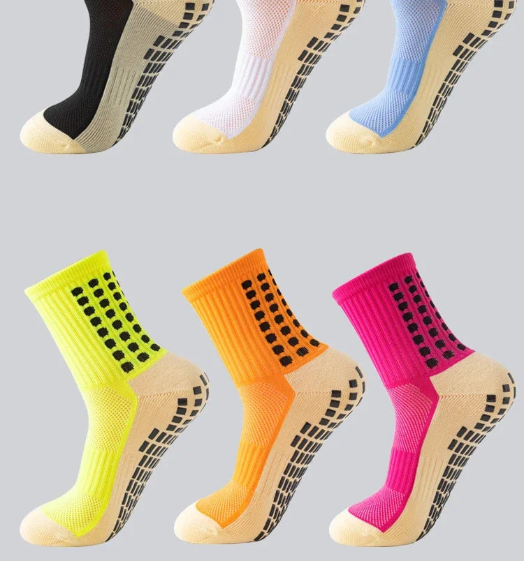 A collection of performance sports grip socks in yellow, orange, and pink colors shown from the side.