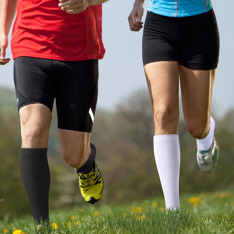 A person wearing black athletic shorts and compression socks is running outdoors.