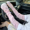 A person wearing pink UV protection arm sleeves is driving a car, holding the steering wheel.