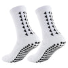 A pair of white non-slip athletic grip socks featuring black chevron and dot patterns.