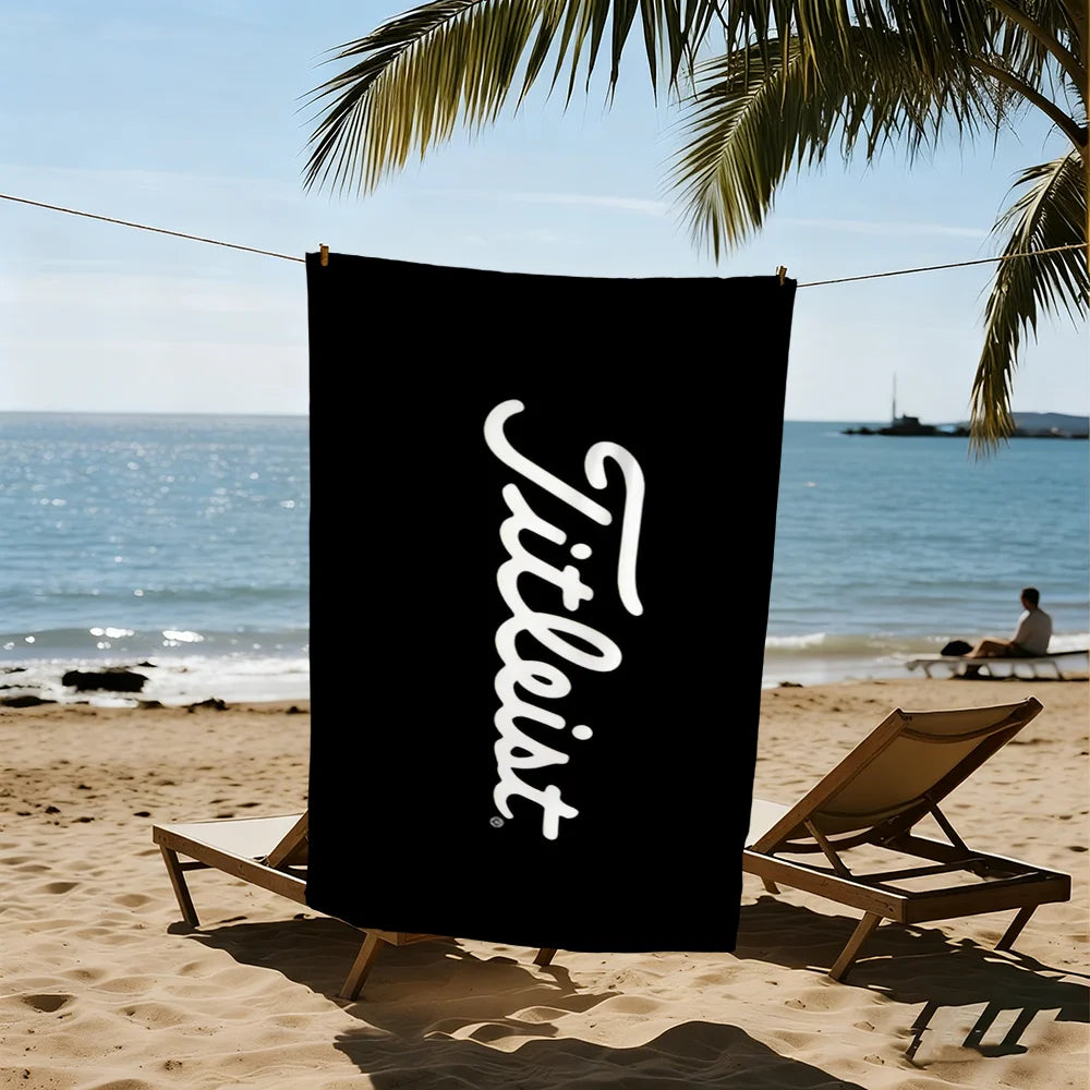 A black beach towel with the word 'Tiltless' written in white script is hanging on a line near the ocean.