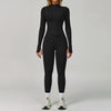 Eine Frau trägt ein schwarzes, nahtloses Sport-Yoga-Set mit langärmeligem Oberteil und Leggings.