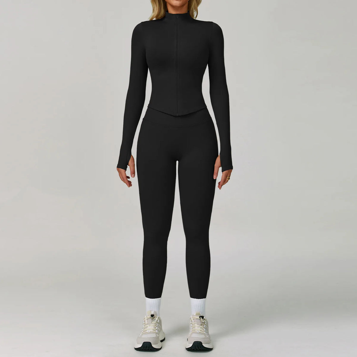 Eine Frau trägt ein schwarzes, nahtloses Sport-Yoga-Set mit langärmeligem Oberteil und Leggings.