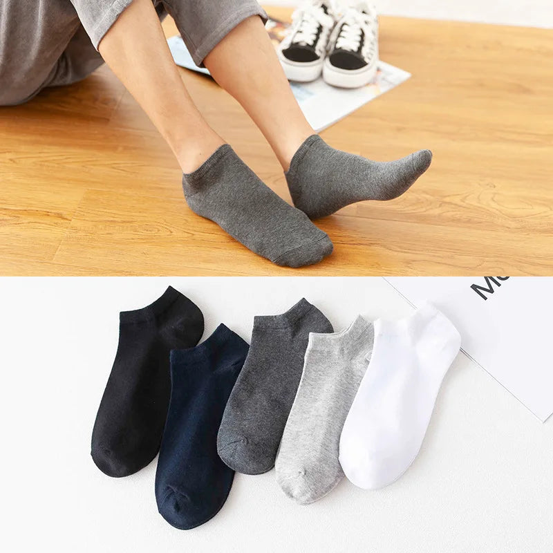 A collection of soft lightweight ankle socks in various shades of gray and black are shown on a wooden surface.