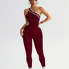 A model wearing a maroon seamless yoga jumpsuit with white trim, posing against a light gray background.