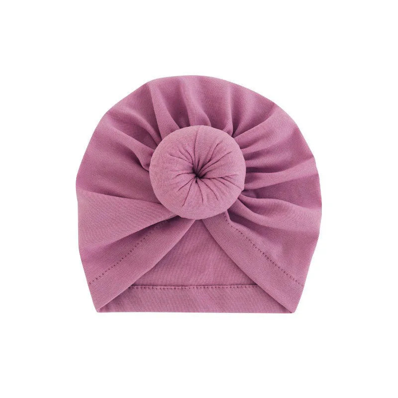 Ein fester mauvefarbener Baumwoll-Babyturban, gefaltet in eine Rosette.